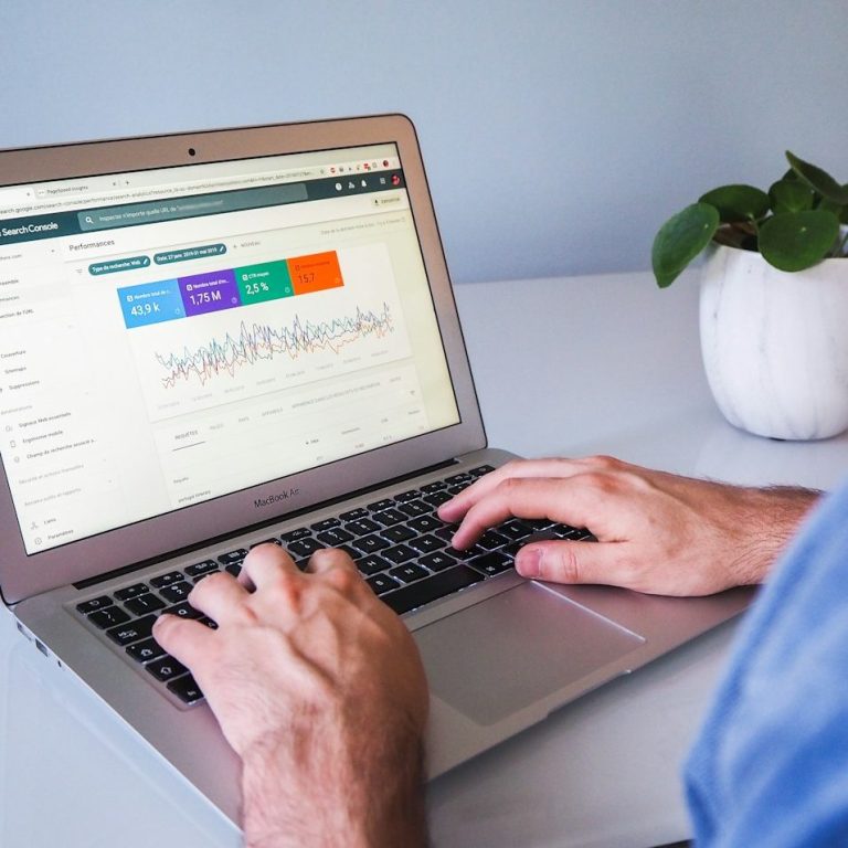 Ein Mensch tippt auf einem Laptop, während er Daten in einem Dashboard analysiert.
